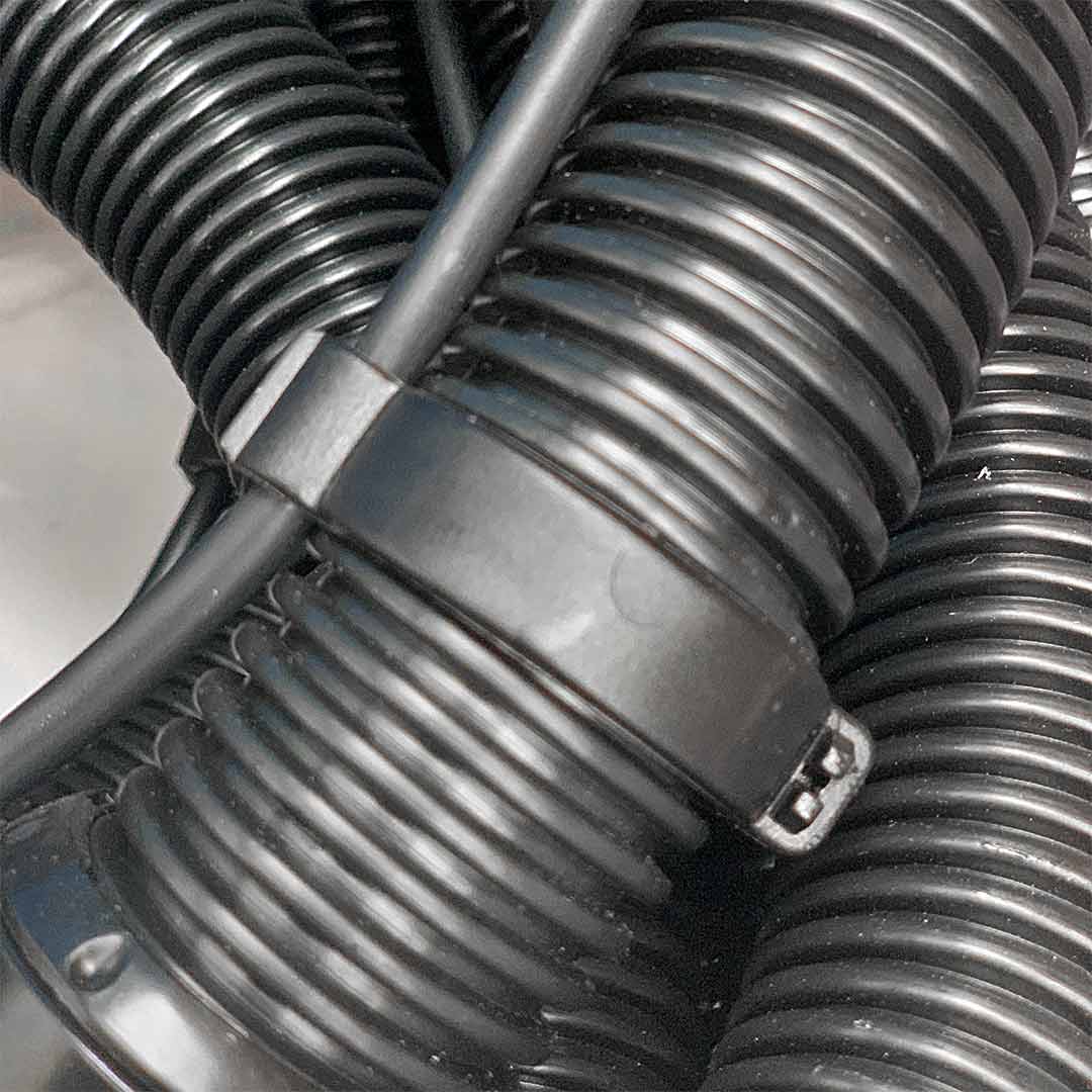 The black water hose clip securely attached to Aqua Pro Vac's vacuum hose, shown in a close-up view.