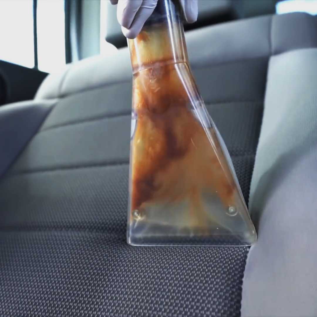 Aqua Pro Vac - Close-up action view of upholstery cleaning nozzle extracting dirt and grime from a car seat.